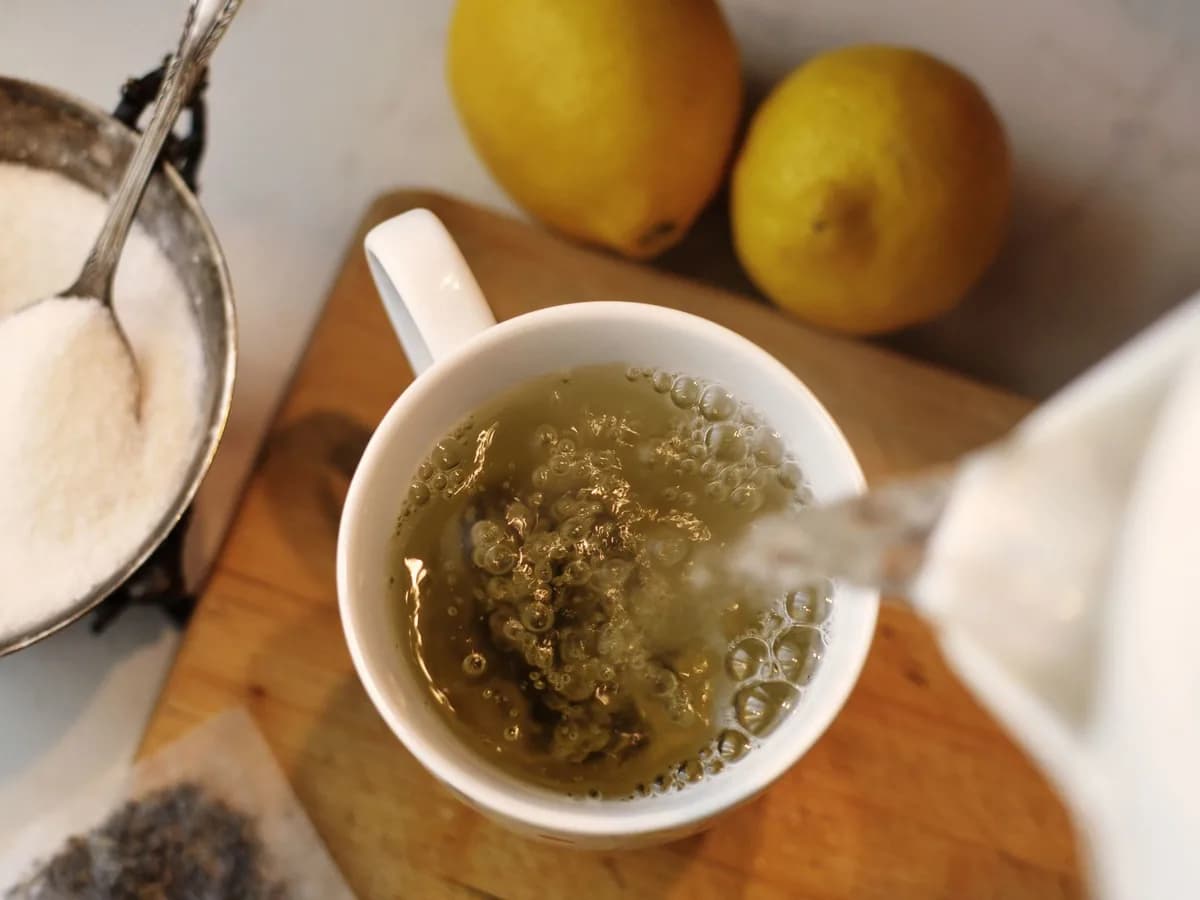 Top view of pouring fresh hot tea with lemons and sugar on the side. Perfect for a cozy morning.