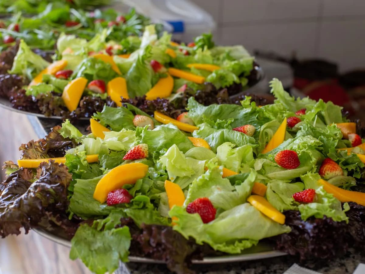Close-up of fresh mixed fruit and lettuce salad platter with vibrant strawberries and mango slices.
