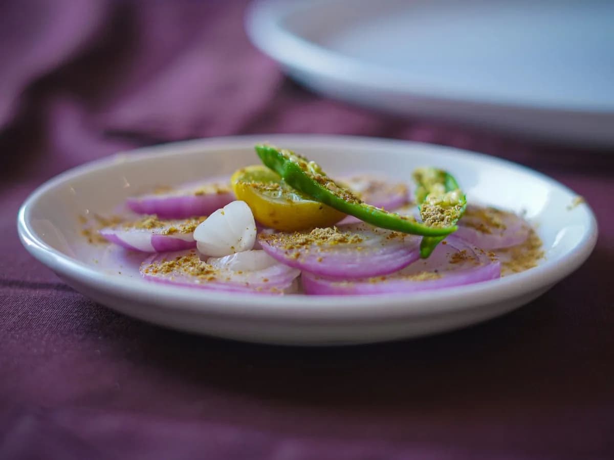 A colorful onion salad garnished with green chili and spices in an artistic presentation.