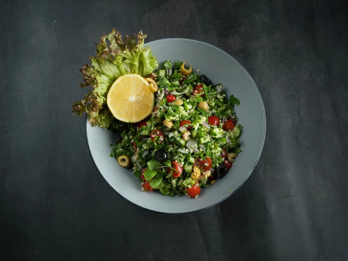 Top view of a vibrant Lebanese tabbouleh salad with fresh ingredients and a lemon garnish.