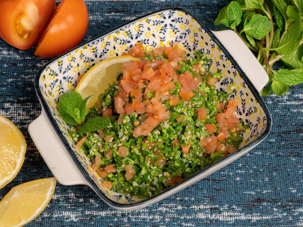 Colorful tabbouleh salad with tomatoes, lemon, and mint served in a decorative bowl for a delicious meal.
